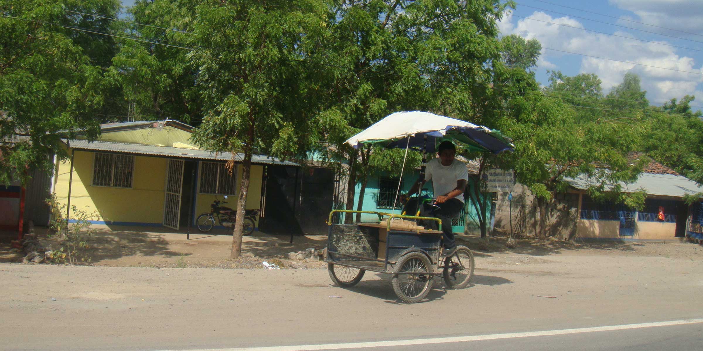 man riding tricycle transport card on road shoulder