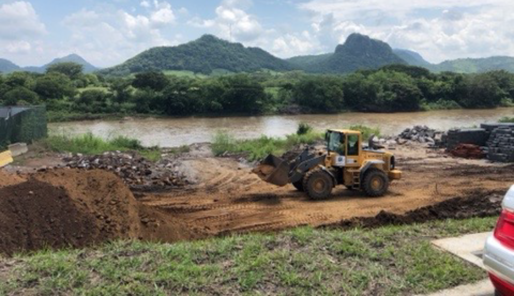 An earth mover clearing site prior to construction. Background is looking across into Honduras.