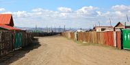 A dirt road in Mongolia with houses on either side.