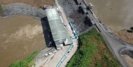Aerial view of the dam at Mt. Coffee Hydropower Plant, with a reservoir on one side and the St. Paul River on the other side.