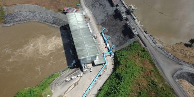 Aerial view of the dam at Mt. Coffee Hydropower Plant, with a reservoir on one side and the St. Paul River on the other side.