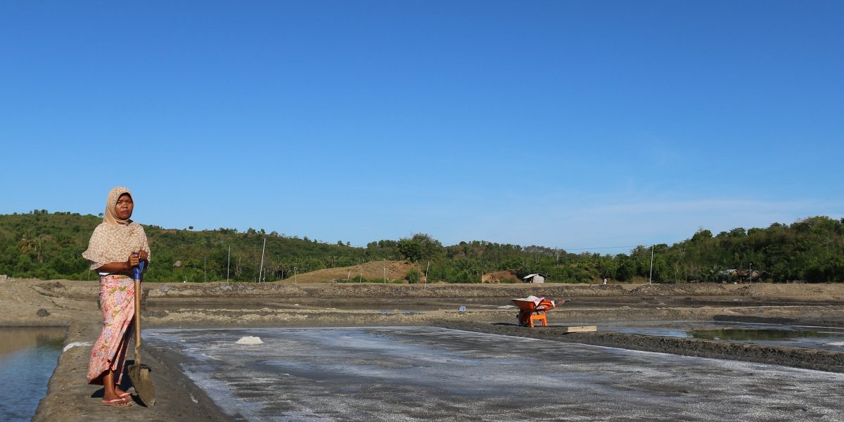 Mini Asmayanti stands between shallow ponds known as salterns from which salt is extracted in Lombok, Indonesia. MCC investments in Indonesia are introducing sea salt producers like Mini to everything from new labor-reducing, energy-efficient technologies to financial management and marketing training to boost production and incomes.