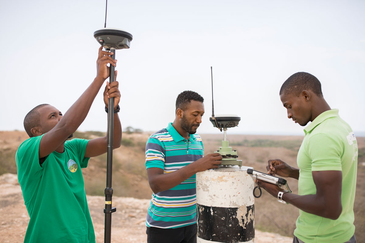 Photo of three men in Cabo Verde working to survey and geomap a property on the island of Maio as part of the MCC-Cabo Verde Compact for the purposes of clarifying land parcel rights and boundaries.