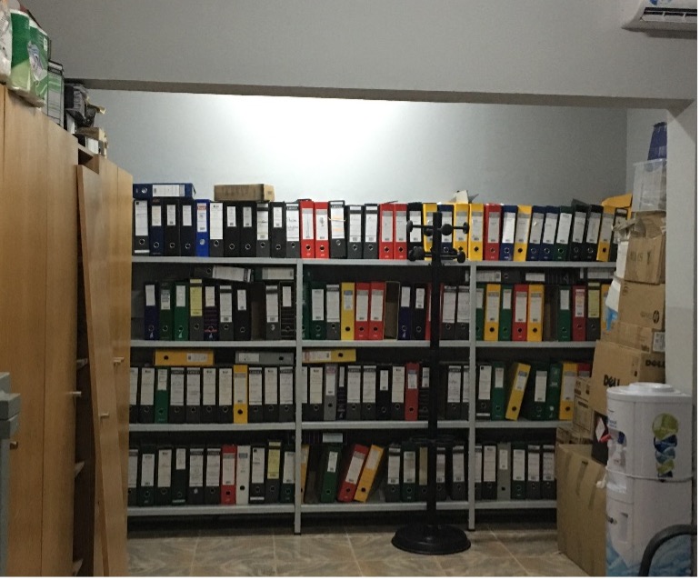 Archive of property registrations. There are full shelves of binders or records in a storage room.