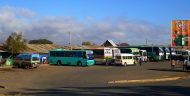 Short- and long-haul buses waiting to load passengers at the bus station in Tunduma, providing service along the Tunduma – Sumbawanga road.