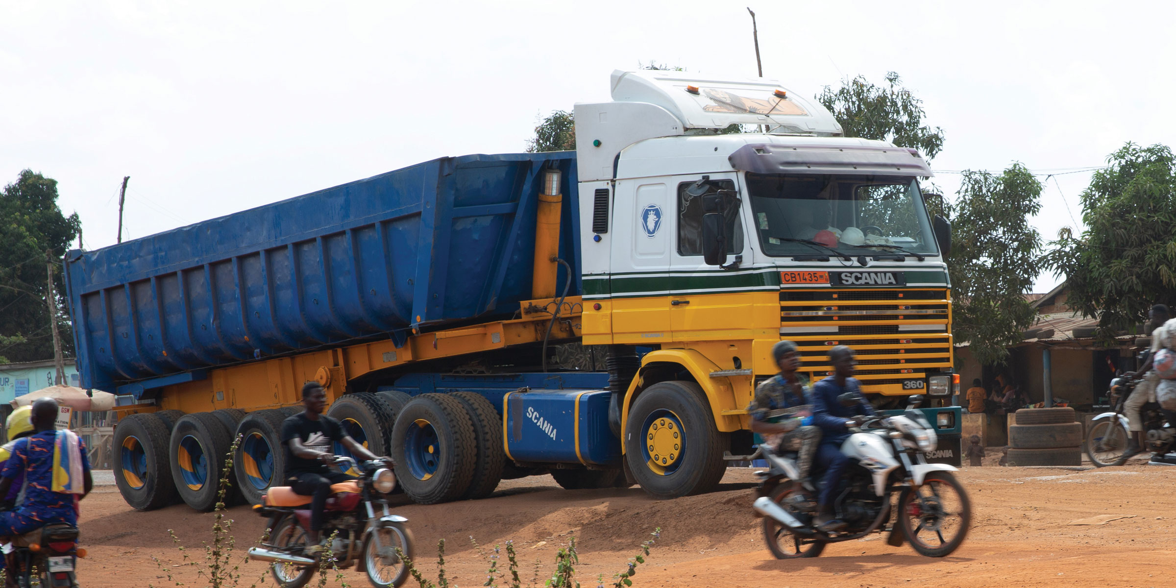 Vehicles and motorbikes on a dirt road.