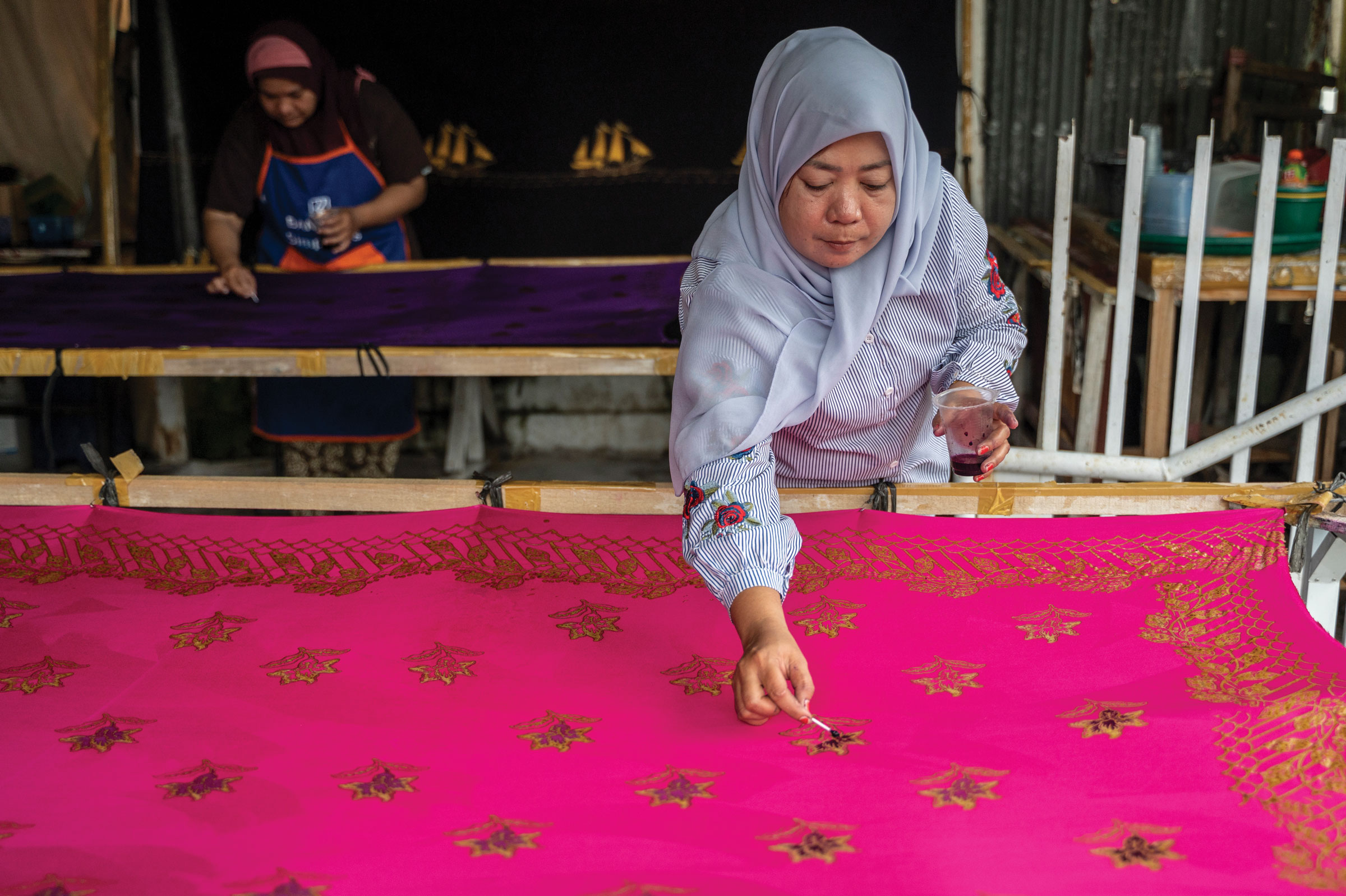 A woman paints fabirc; The Philippines.