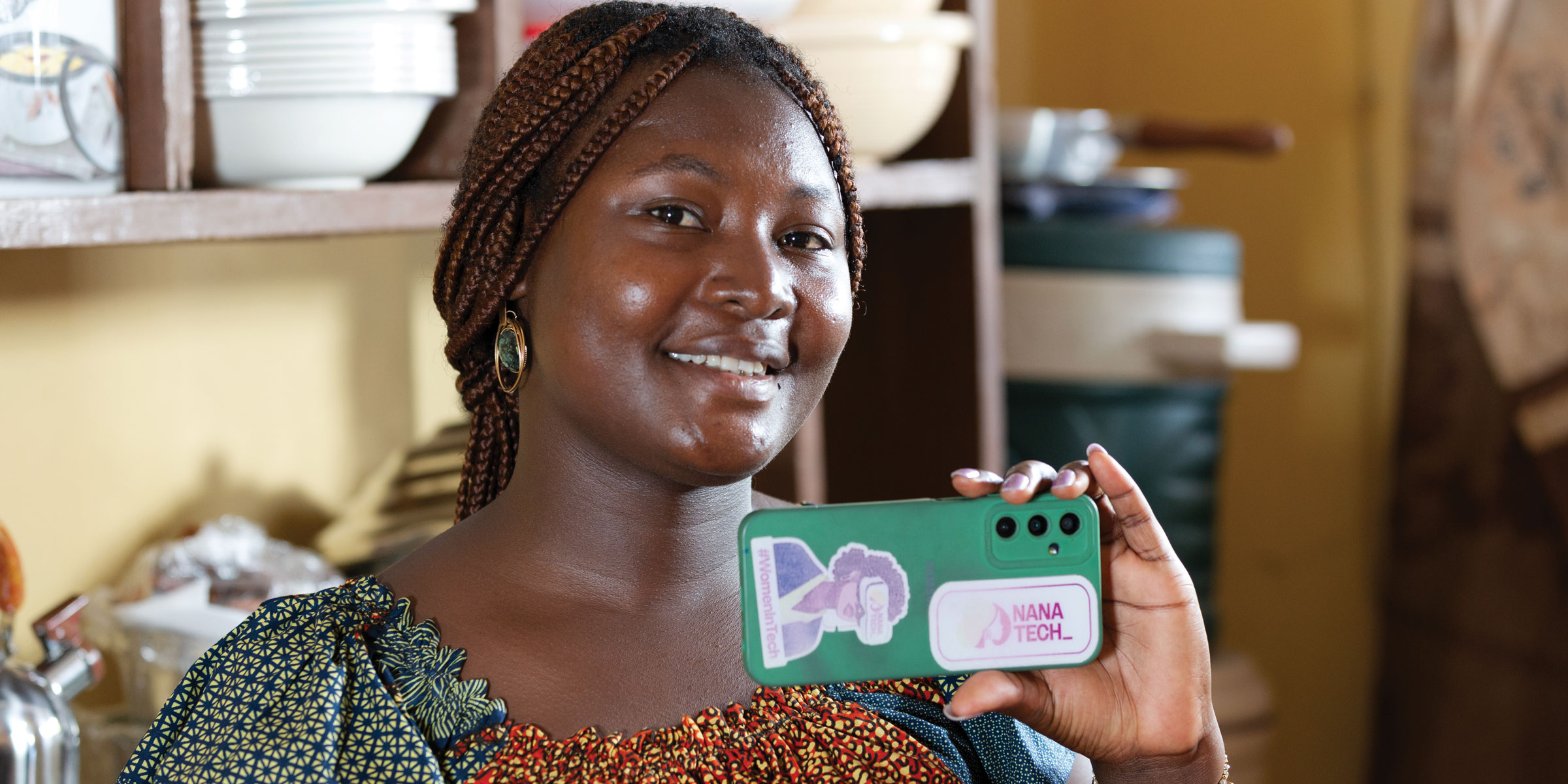 A young woman in Togo holding up her mobile phone.