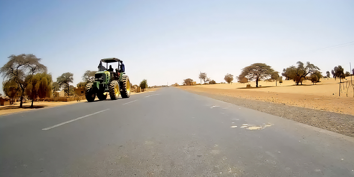 A tractor drives on a paved road