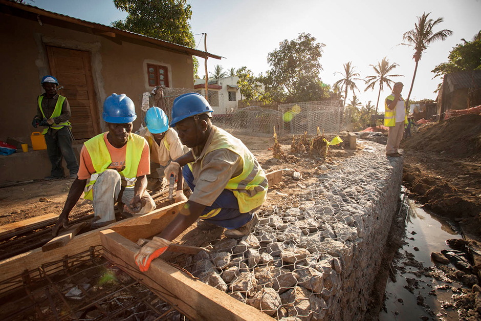 Workers install drainage equipment in Nampula as part of the Mozambique Compact. Residents say improper drainage leads to marshy soil, stagnant water and the spread of disease.